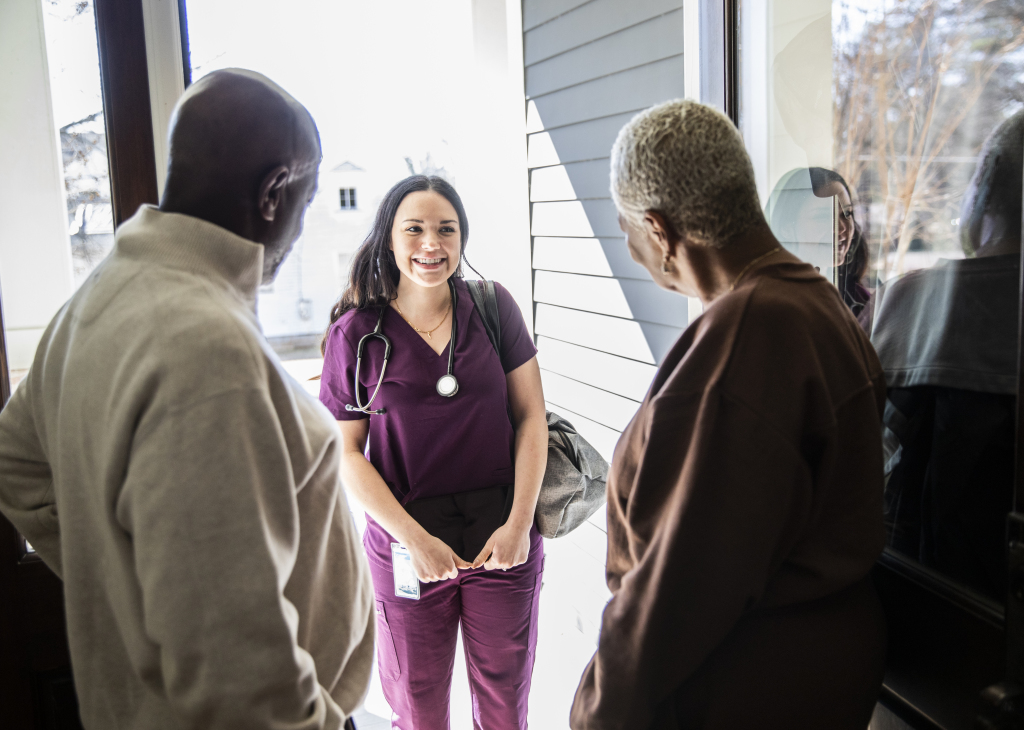 Senior couple greeting in-home nurse at their front door